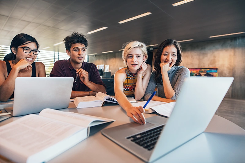 Grupo de pessoas diversas olhando para a tela de um notebook