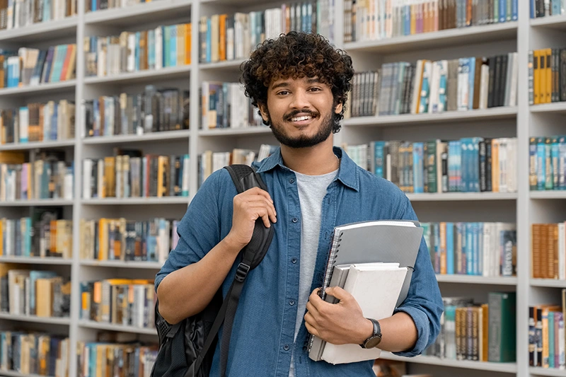 Jovem segurando material escolar e sorrindo